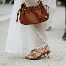 woman wearing white dress, brown sandals, and brown bag 
