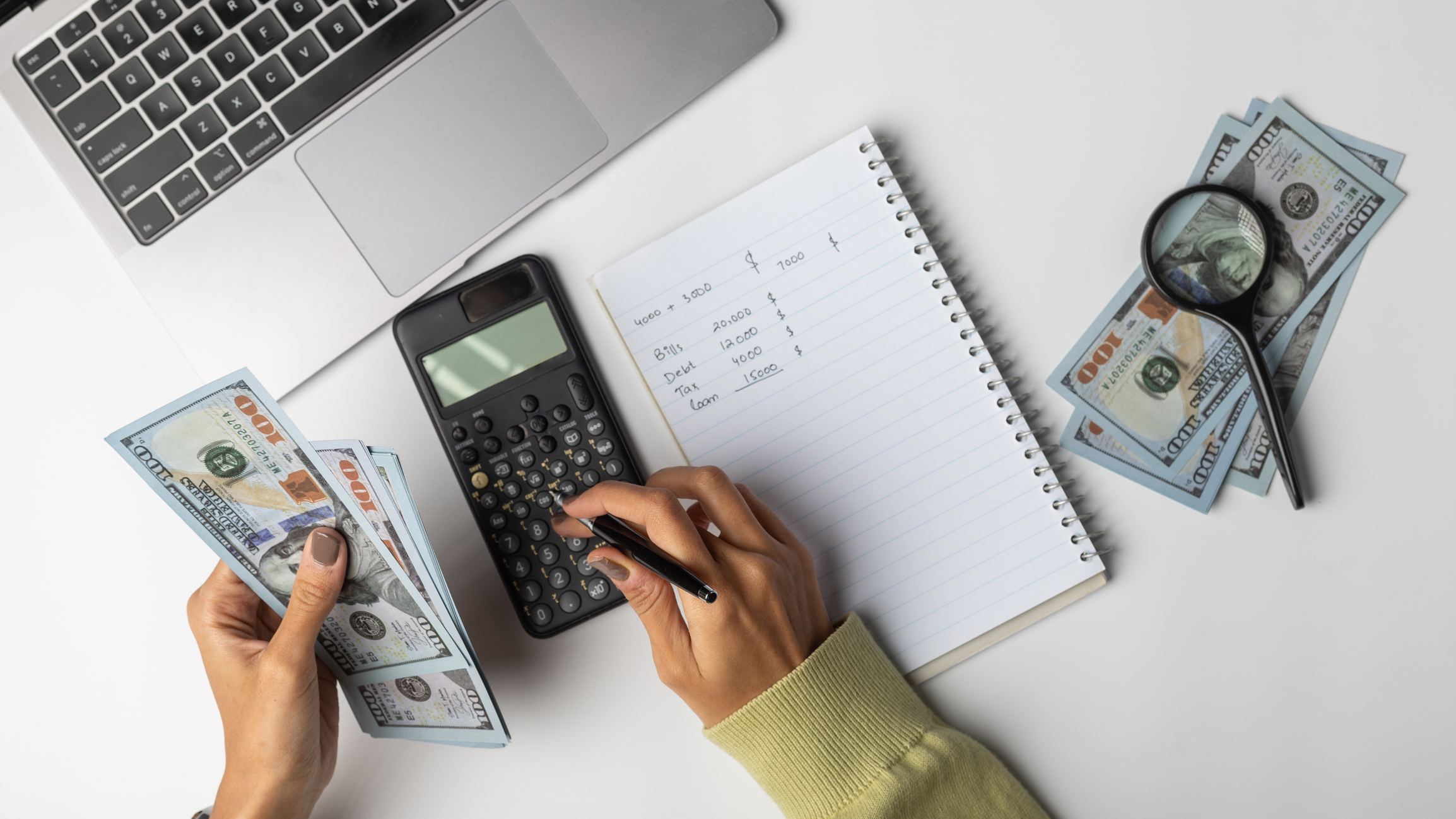 Calculating expenses with cash and calculator at a work desk while managing finances