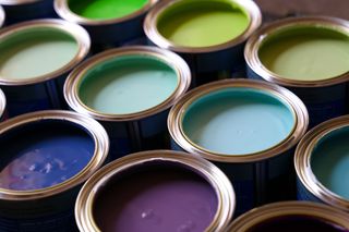 Open tins of brightly coloured paint in rows.