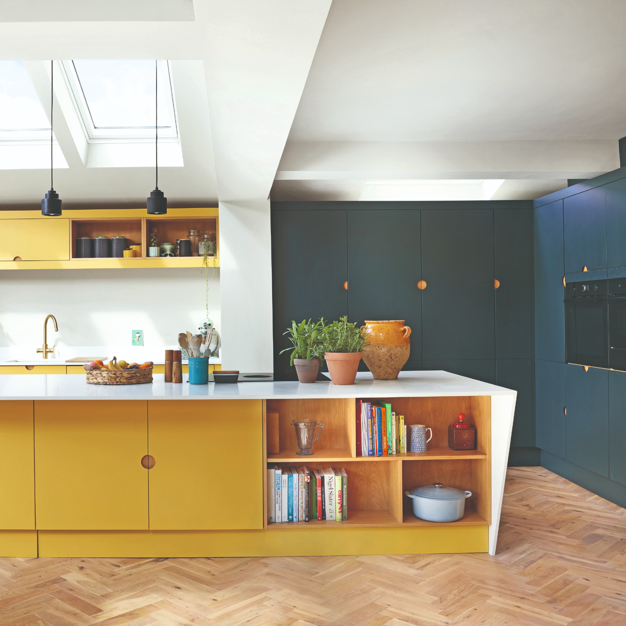 A two-tone kitchen with half of the cabinets and the island in yellow and the other half in teal blue