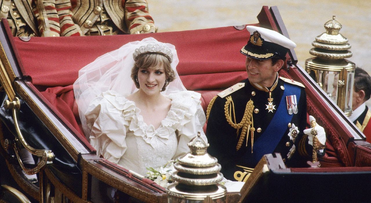 Prince Charles, Prince of Wales and Diana, Princess of Wales, wearing a wedding dress designed by David and Elizabeth Emanuel and the Spencer family Tiara, ride in an open carriage, from St. Paul&#039;s Cathedral to Buckingham Palace, following their wedding on July 29, 1981 in London, England. 