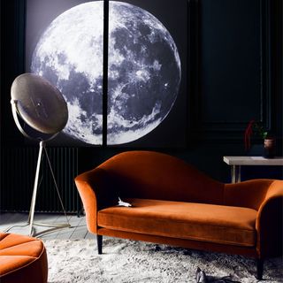 printed canvas of moon on wall and orange sofa