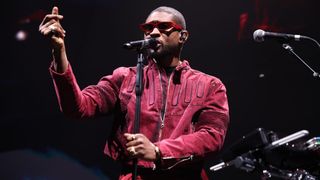 Usher performing in a red jacket and sunglasses 