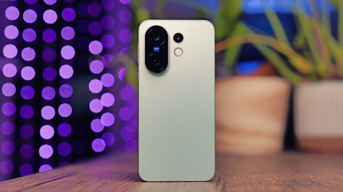 Vivo X200 FE phone on a wooden desk with some lights behind it