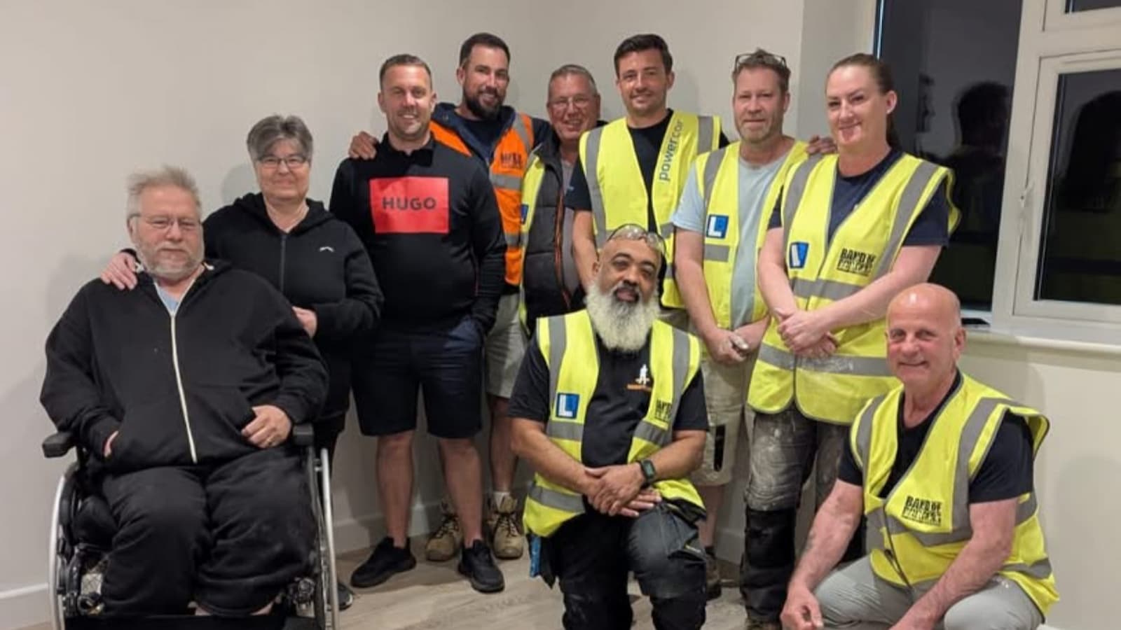 A team of builders with a paralysed man and his wife inside a new extension