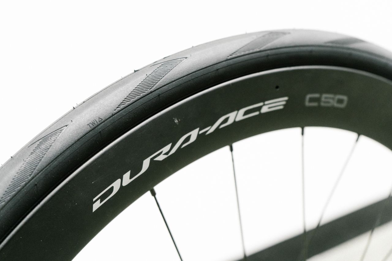 An aero road wheel stands against a white wall