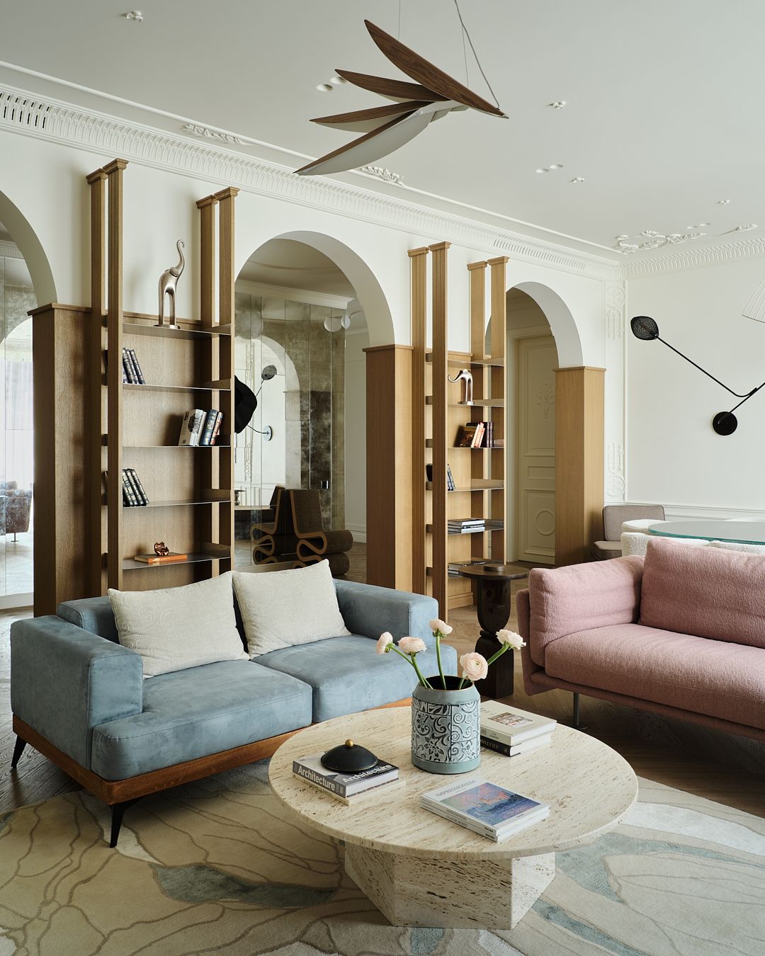 A photo of a living room with three arches, a blue couch and a pink couch