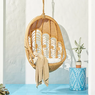 A wicker hanging egg chair beside a potted plant.