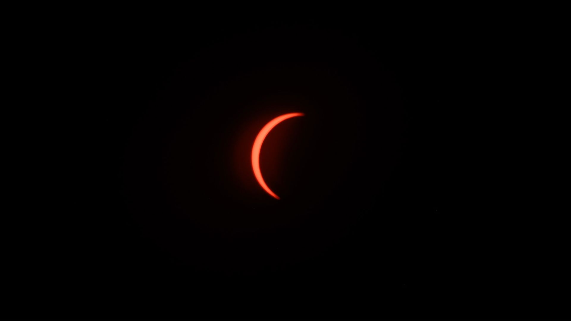 The eclipsed sun is photographed in a black sky during the partial phase of a total solar eclipse.