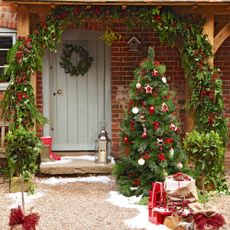 Green door with festive garland and mistletoe