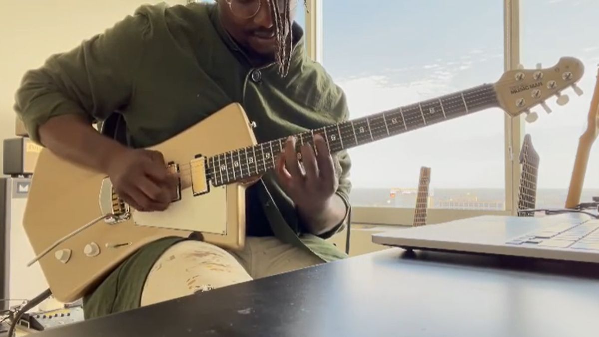 Tosin Abasi playing a St. Vincent signature Goldie Ernie Ball Music Man guitar