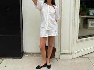 Woman in white shorts and ballet flats.