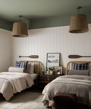 calming bedroom with twin beds, white panelled walls, sage green ceiling and woven ceiling lights