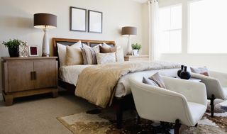 A clean bedroom with armchairs at the foot of the bed