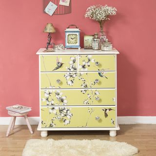 yellow drawer with pink wall and clock