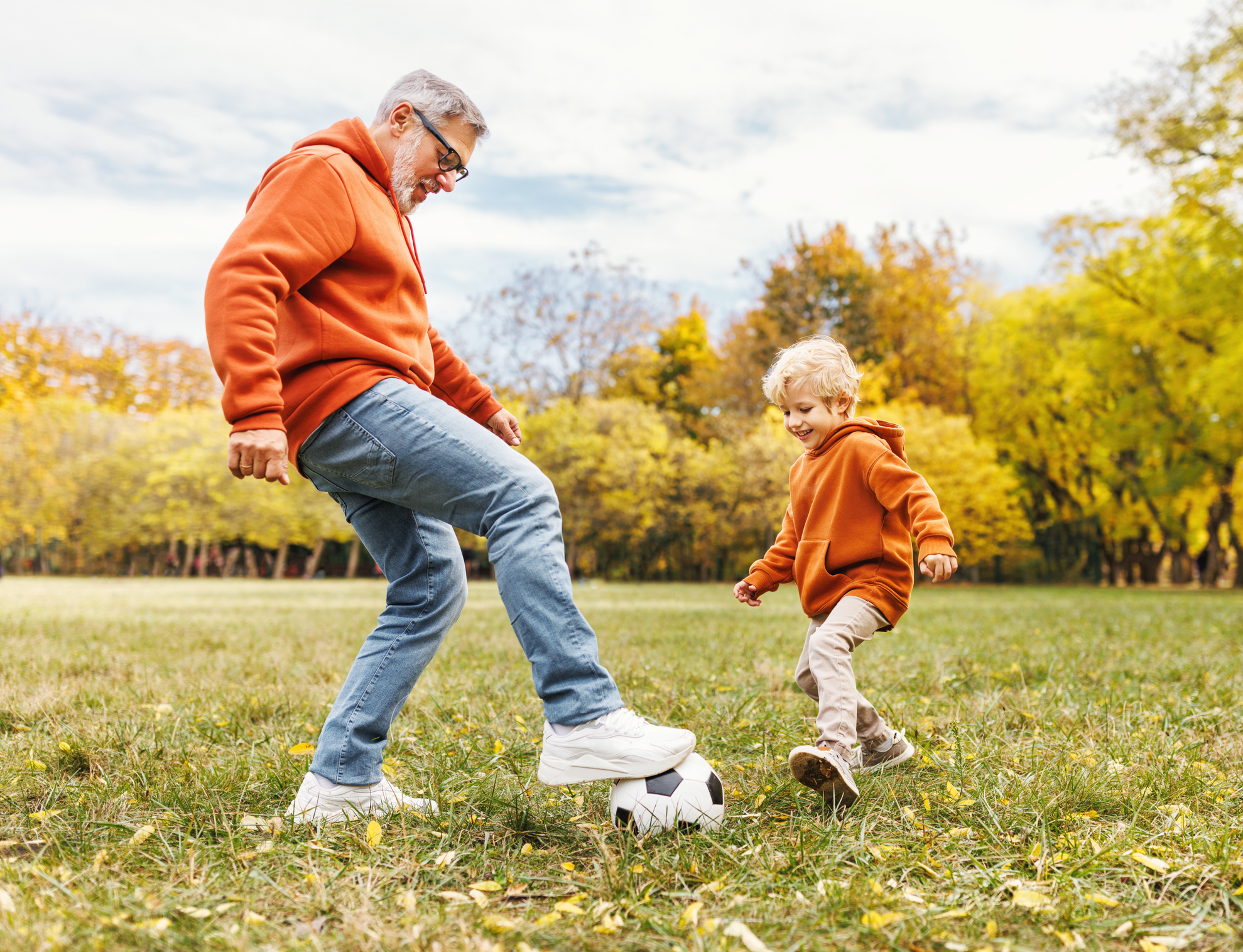 Happy family grandfather and grandson play football on lawn in the park