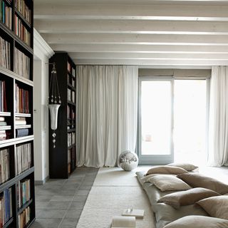 attic living area with white curtain and book shelf