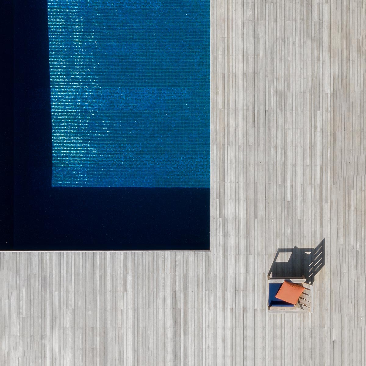 Aerial view of a blue swimming pool with a chair to the side