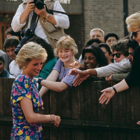 Princess Diana greeting fans leaning over a fence