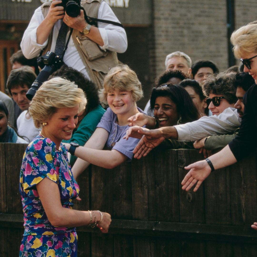 Princess Diana greeting fans leaning over a fence