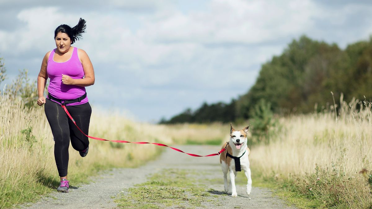 Woman running with her dog through a field