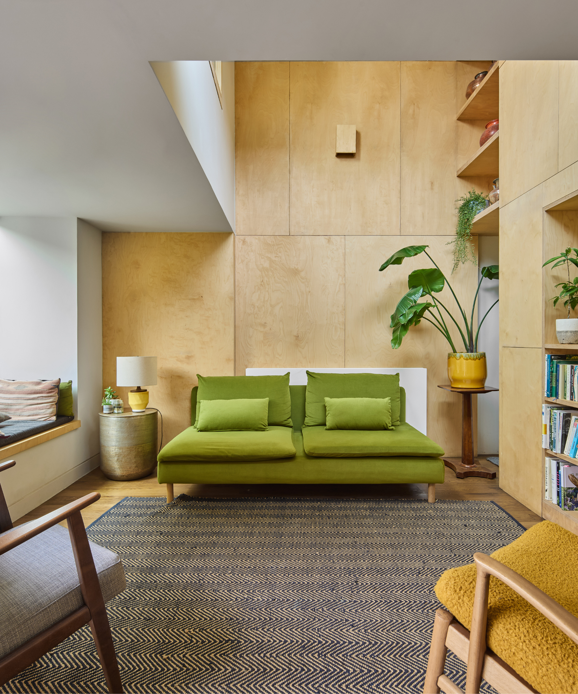 Living area with green sofa, built-in bookshelf and window seat