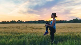 Woman stretching during run at sunset