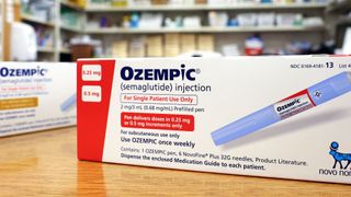 two boxes of the medication "ozempic" sit on a wooden table in a pharmacy