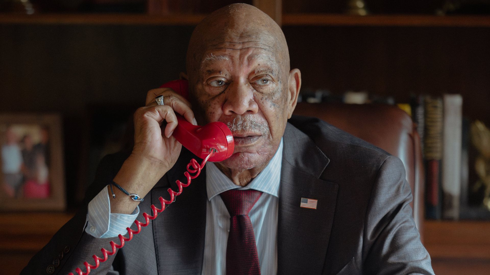 Morgan Freeman speaks into a red corded telephone