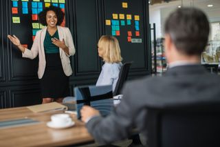 Woman giving pitch in front of wall of post-it notes