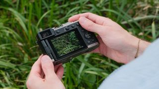 Panasonic Lumix L10 camera held in both hands with lens extended.