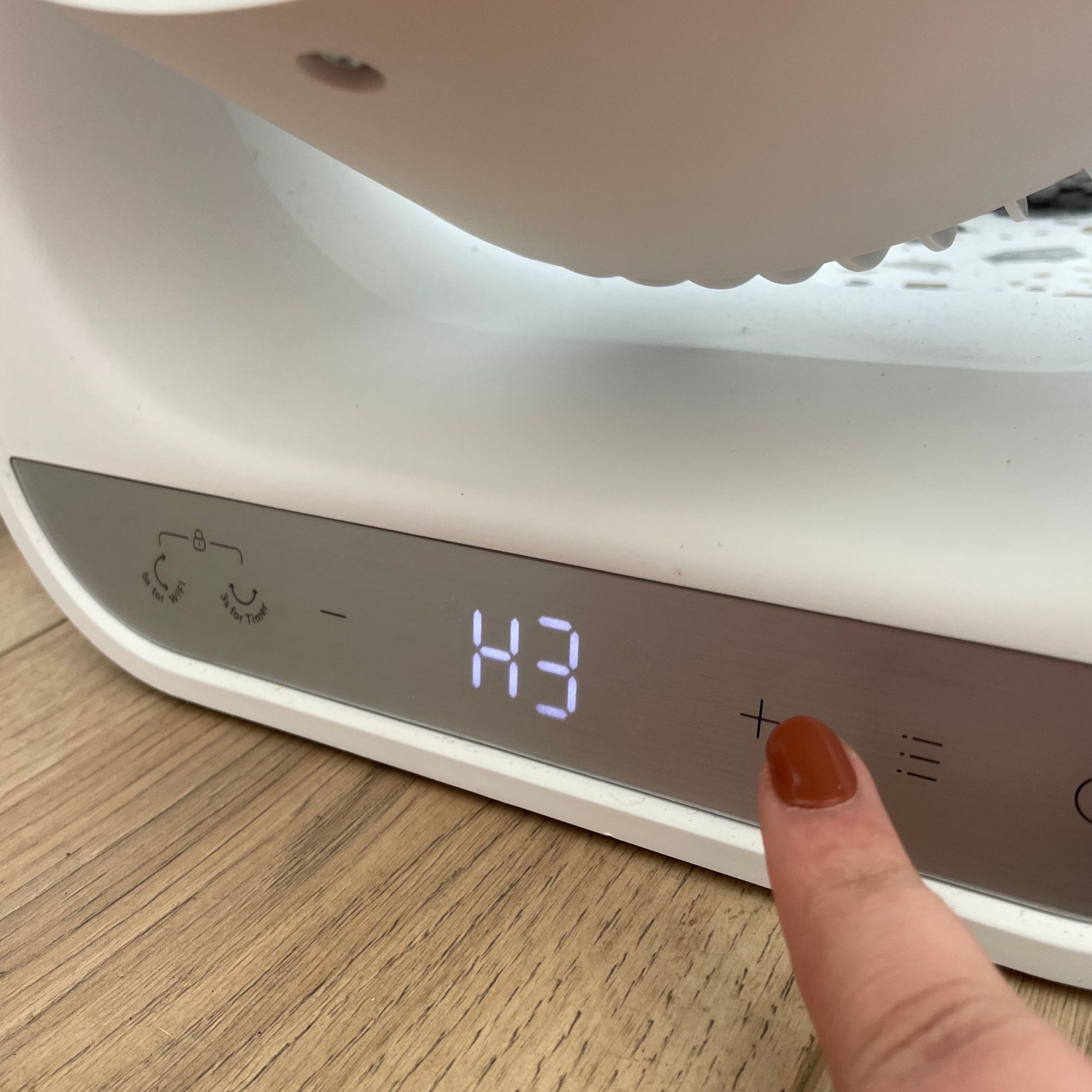 Finger pushing buttons on the screen of the Dreo Smart Whole Room Heater 714S