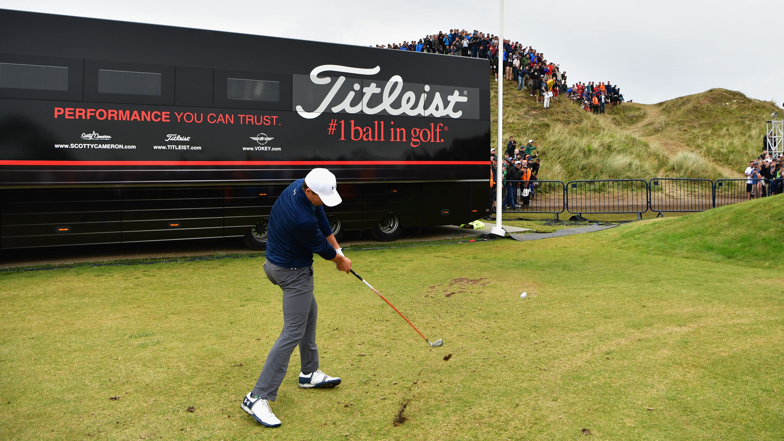 Jordan Spieth plays a shot from the driving range in front of a Titleist tour truck at the 2017 Open