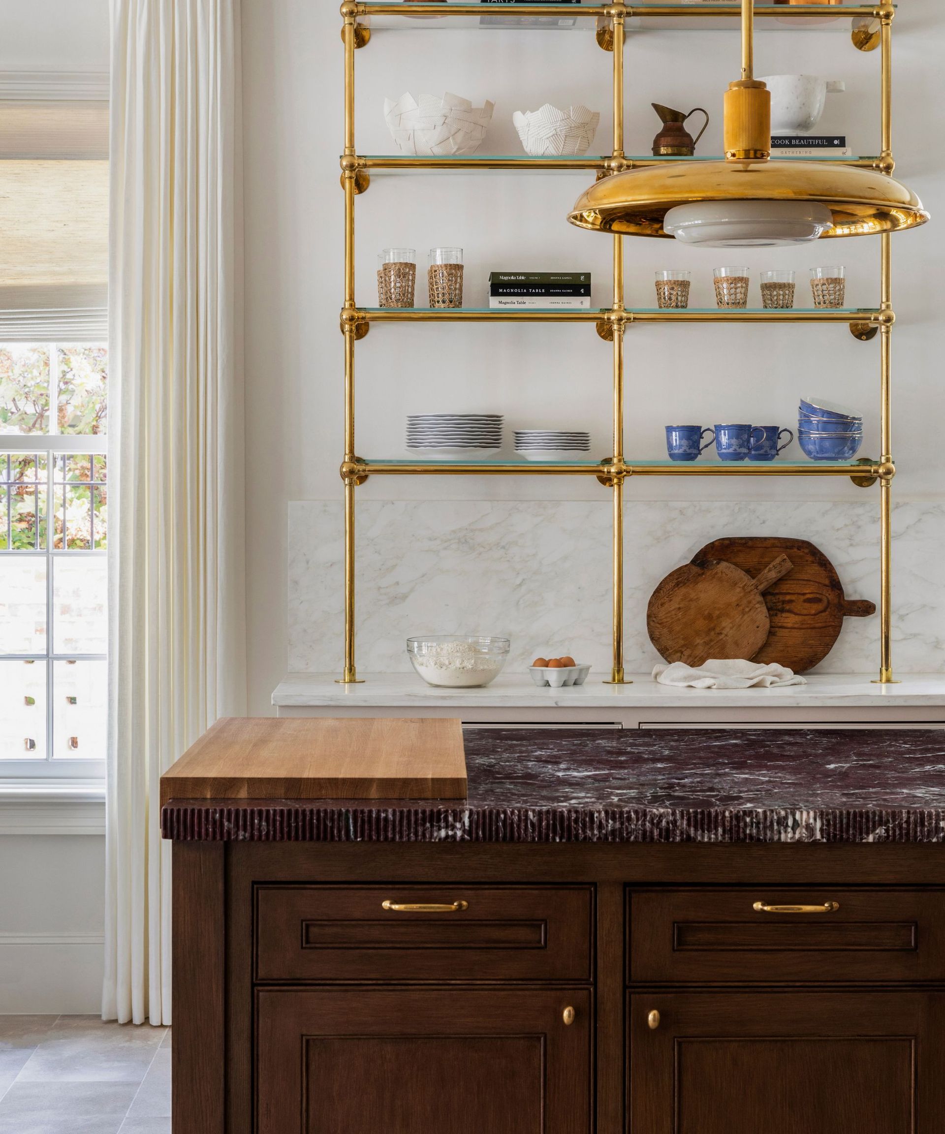 A dark wood kitchen island with brown marble countertops and a custom wooden cutting board added to the end of the counters
