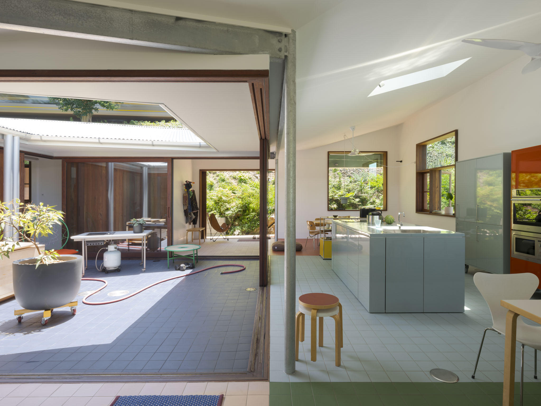 a white boxy house, scarborough house in australia, among wooded setting and with colourful furniture
