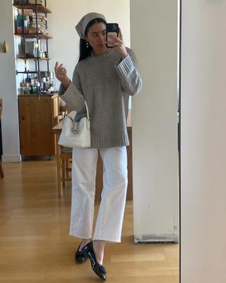 Woman wearing a sweater, white jeans, and ballet flats