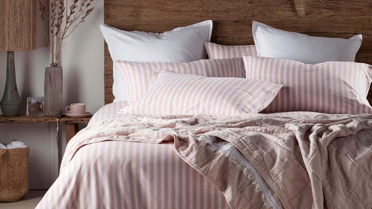 A bedroom with a bed covered in pink and white striped brushed cotton bedding