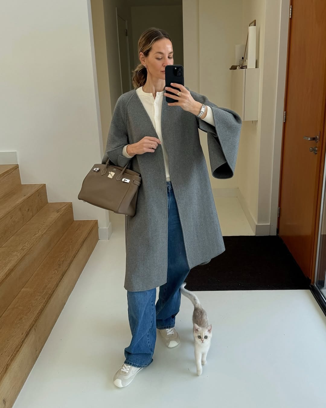 @anoukyve wearing jeans, white sneakers, grey coat, white button-down, and top handle bag