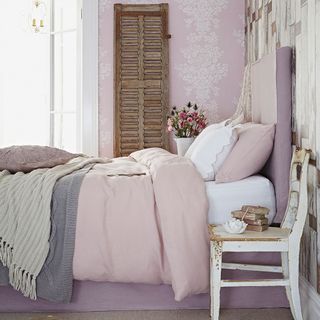 bedroom with pink wall pink bed with white and pink cushions and wooden chair