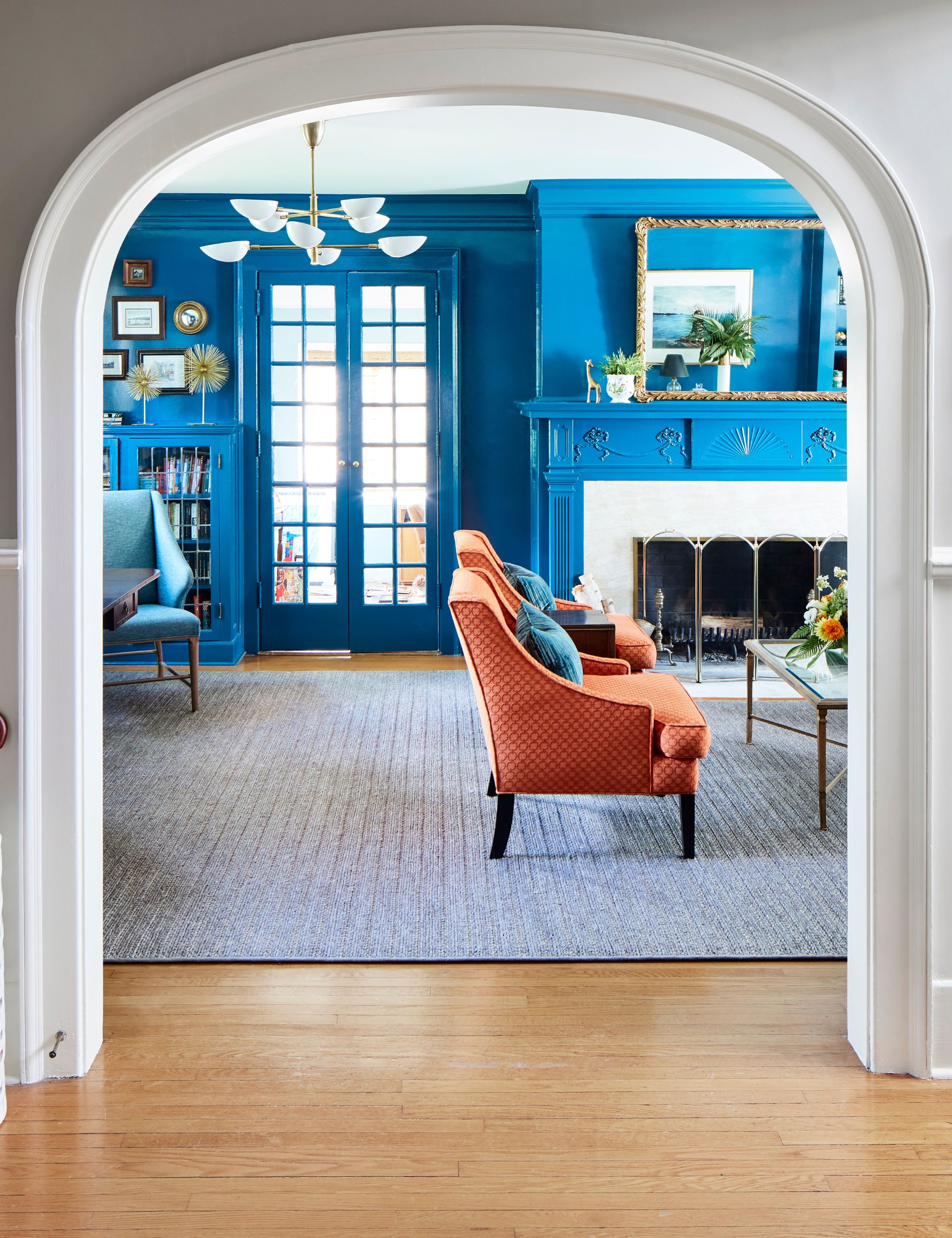 View through an archway into a blue living room with orange seating