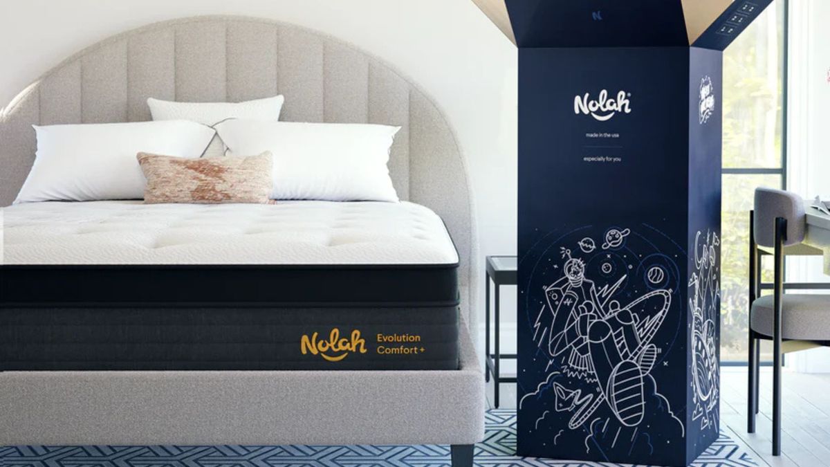 The Nolah Evolution Comfort + Mattress on a gray bed frame. To the bed's right, the mattress's shipping box stands upright.