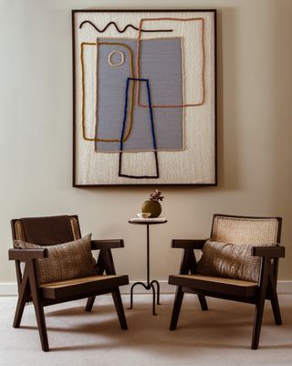 A wall painted in fawn with a pair of dark brown chairs