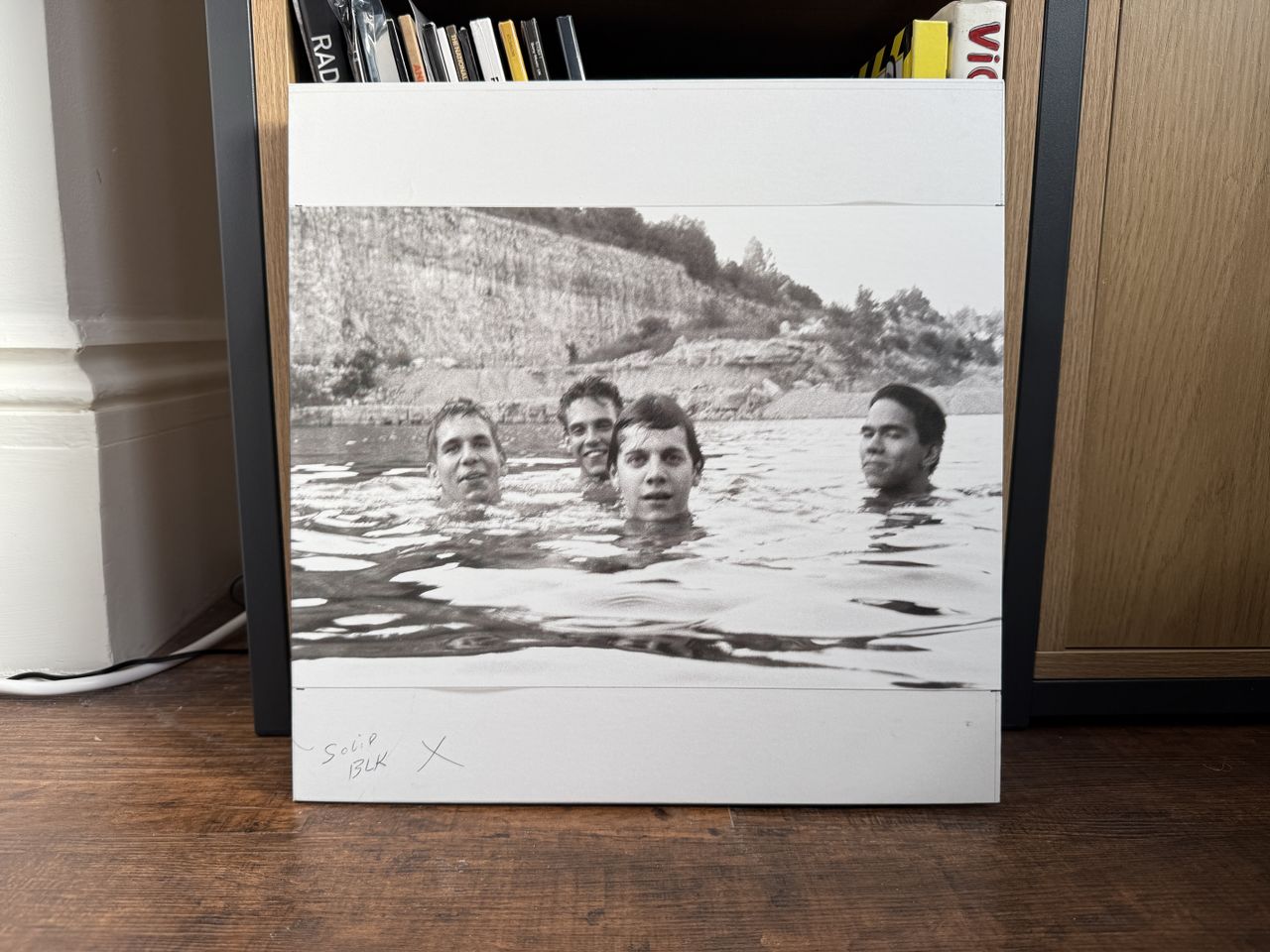 The monochrome front cover of Spiderland by Slint. It shows four men swimming in a quarry, their heads floating above the water.