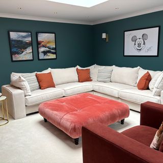 DFS corner sofa and buttoned footstool in large media room, with dark green walls and wall art