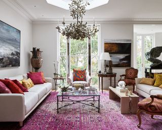 White living room with impressive chandelier and pink rug