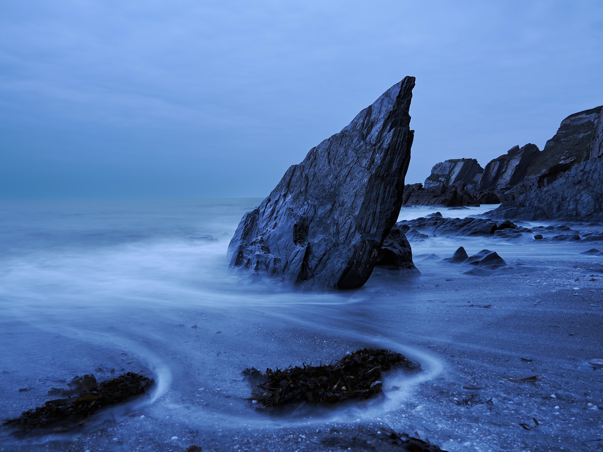 OM System OM-3 sample photos: jagged rock in the ocean, blurred water around it