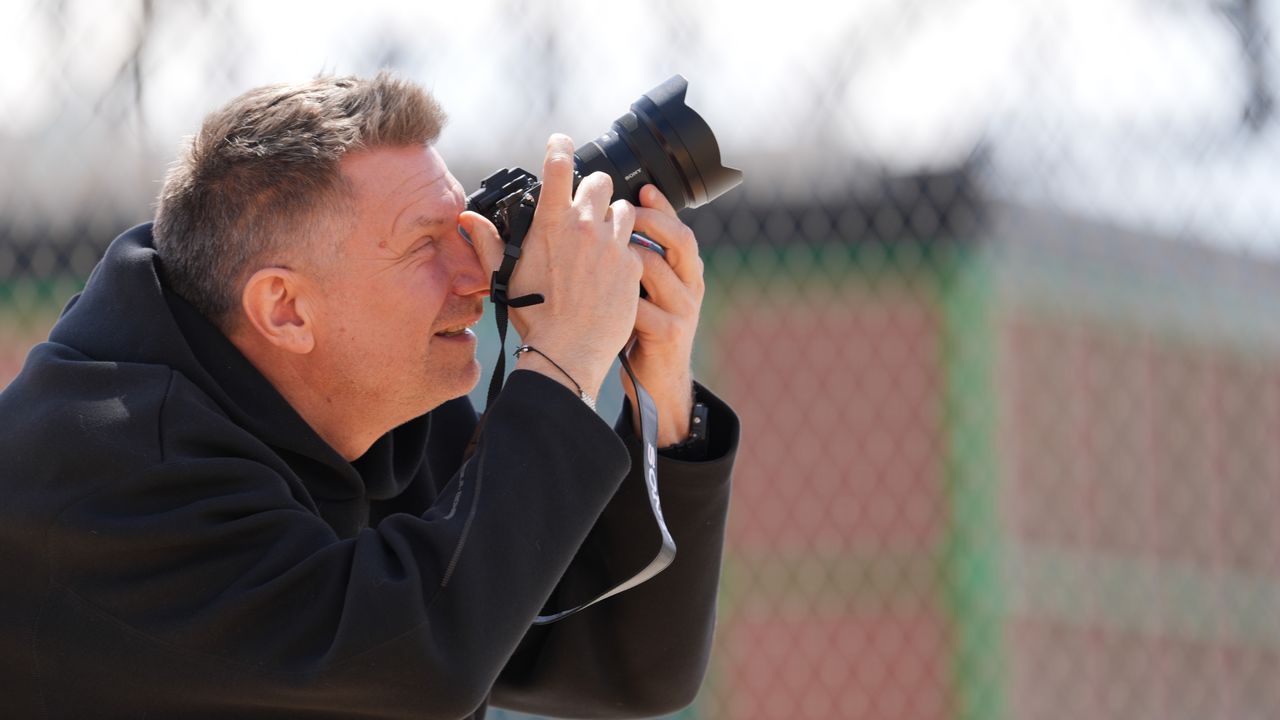 An image of a man taking a photograph on a basketball court.