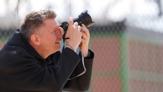 An image of a man taking a photograph on a basketball court.