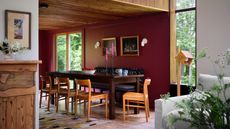 dining room with burgundy paint, timber ceiling, blue banquette seat and timber chairs around dining table