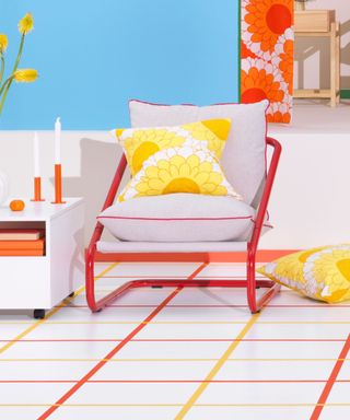 A red chair with gray and yellow cushions in a brightly lit room with a grid floor